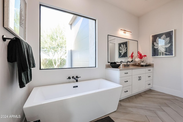 full bathroom featuring a soaking tub, baseboards, and vanity