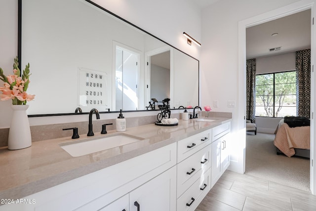 ensuite bathroom with connected bathroom, visible vents, a sink, and double vanity