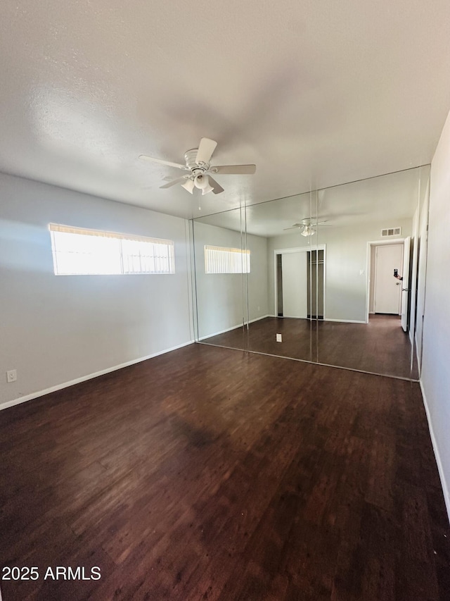 unfurnished bedroom with dark wood-type flooring, a closet, and ceiling fan