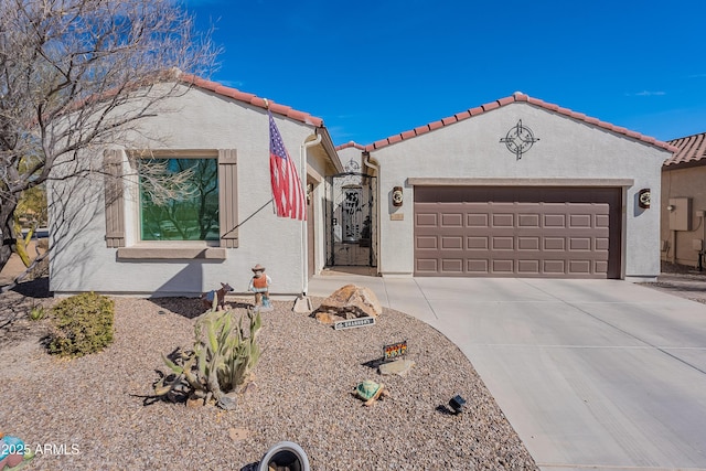 mediterranean / spanish home with concrete driveway, a tiled roof, an attached garage, and stucco siding