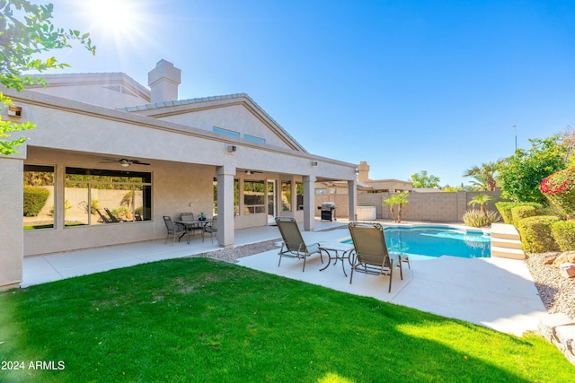 view of swimming pool featuring a lawn, ceiling fan, area for grilling, and a patio area