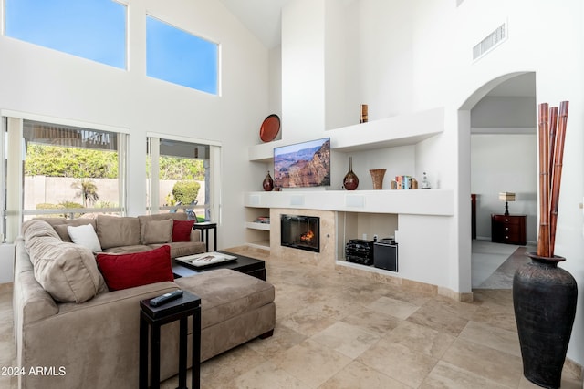 living room featuring high vaulted ceiling and a tiled fireplace