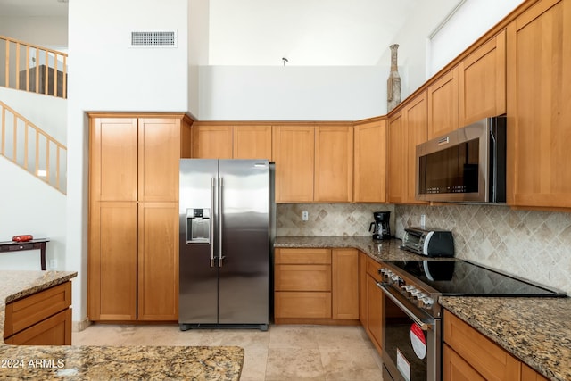 kitchen with appliances with stainless steel finishes, backsplash, and stone countertops