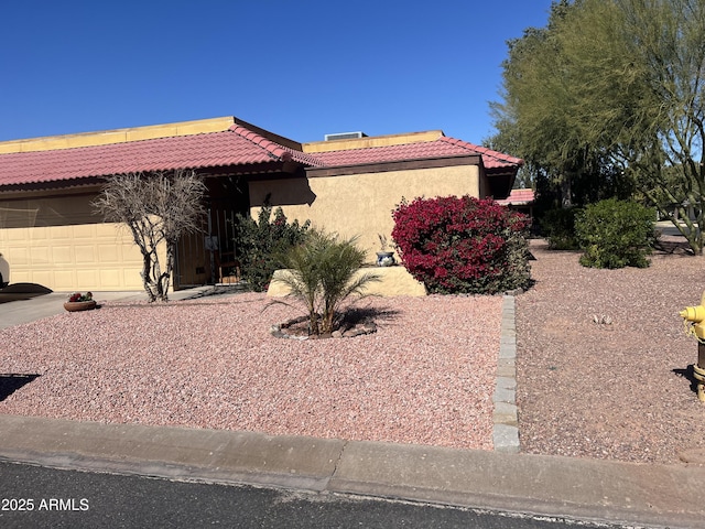 view of front of house with a garage, stucco siding, and a tiled roof