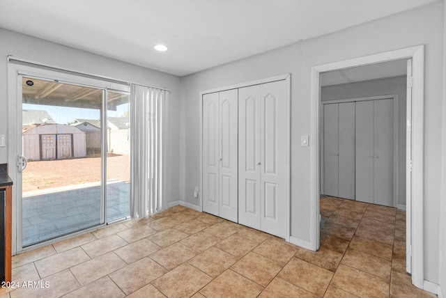 unfurnished bedroom featuring light tile patterned floors, access to outside, and a closet