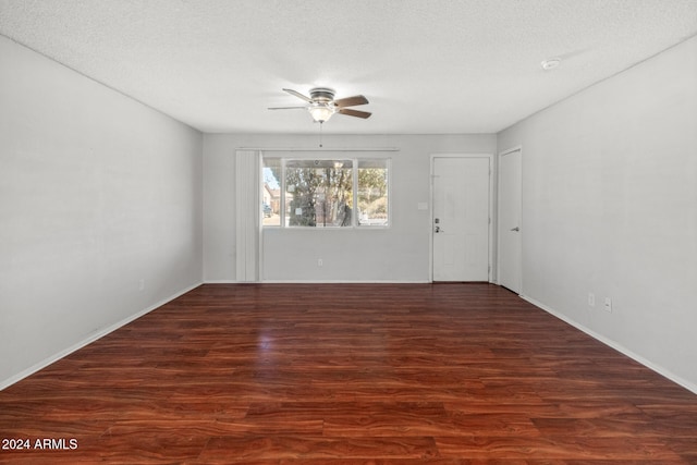 empty room featuring a textured ceiling, ceiling fan, and dark wood-type flooring