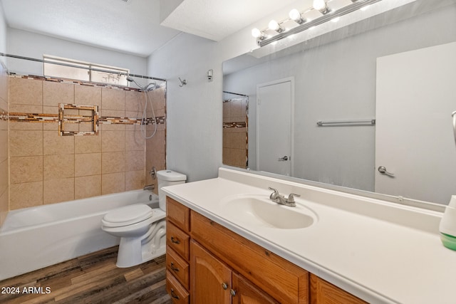 full bathroom featuring vanity, hardwood / wood-style floors, tiled shower / bath combo, and toilet