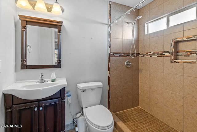 bathroom with vanity, toilet, and tiled shower