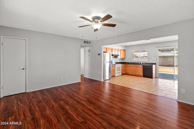 unfurnished living room featuring ceiling fan, sink, a textured ceiling, and light hardwood / wood-style flooring