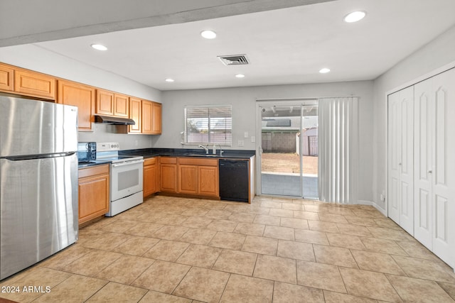 kitchen with sink, electric range, light tile patterned floors, black dishwasher, and stainless steel refrigerator