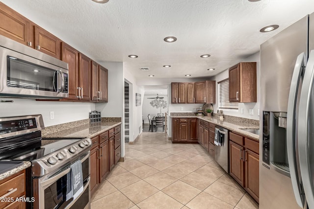 3358 W Sandra Ter, Phoenix, AZ 85053 - kitchen with stainless steel appliances, light tile patterned flooring, recessed lighting, light stone countertops, and a textured ceiling