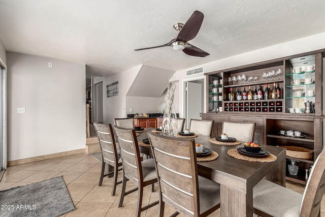 3358 W Sandra Ter, Phoenix, AZ 85053 - dining space featuring light tile patterned floors, ceiling fan, a dry bar, a textured ceiling, and baseboards
