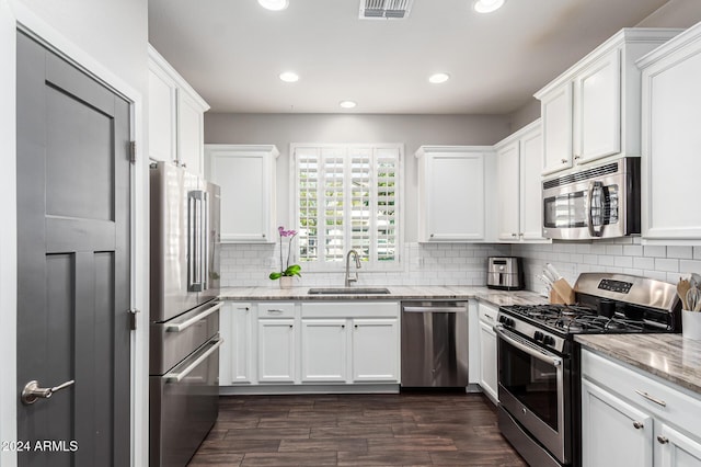 kitchen featuring stainless steel appliances, white cabinetry, a sink, and backsplash