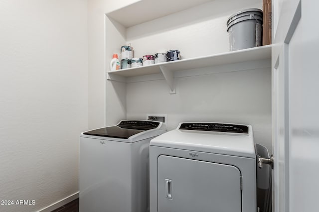 clothes washing area featuring laundry area, baseboards, washing machine and clothes dryer, and wood finished floors