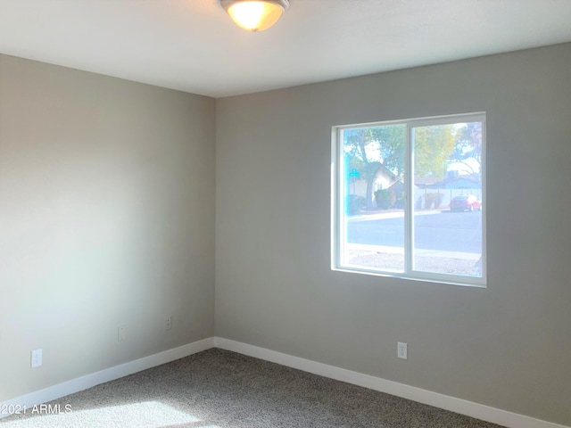 unfurnished room featuring dark carpet and baseboards