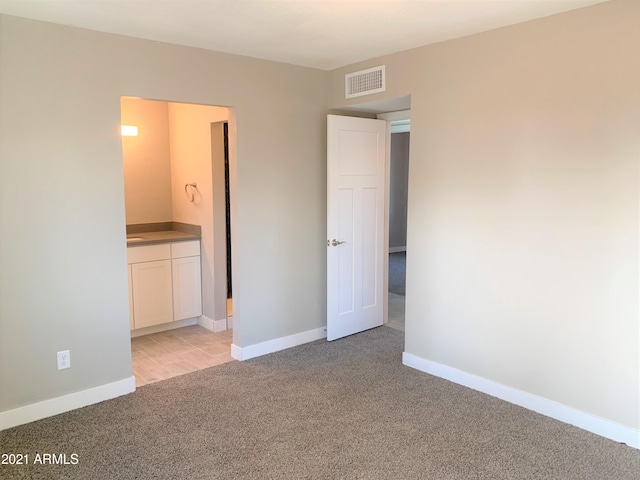 unfurnished bedroom featuring light colored carpet, visible vents, connected bathroom, and baseboards