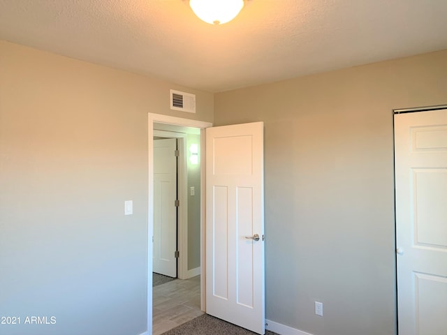 unfurnished bedroom with visible vents, a textured ceiling, and baseboards