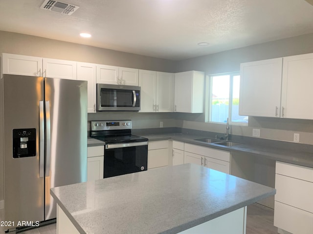 kitchen featuring white cabinets, visible vents, stainless steel appliances, and a sink