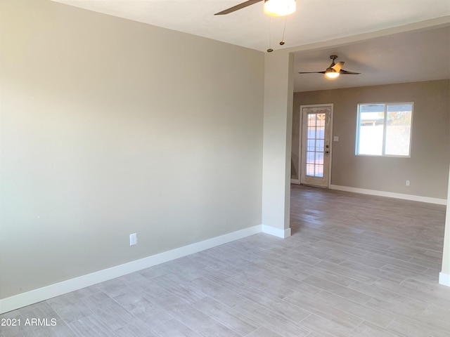 empty room with light wood-type flooring, baseboards, and a ceiling fan