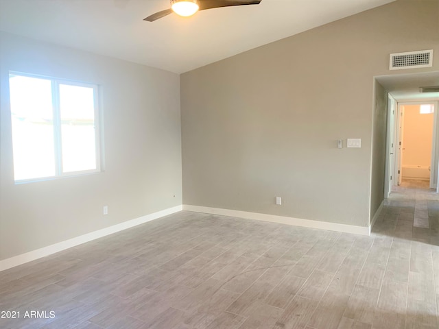 spare room featuring visible vents, baseboards, light wood-style flooring, ceiling fan, and vaulted ceiling