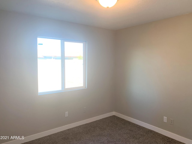 empty room featuring baseboards and dark carpet