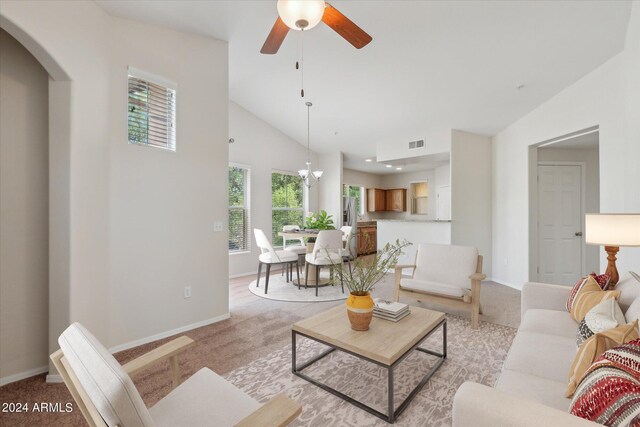 living room with arched walkways, high vaulted ceiling, light carpet, visible vents, and baseboards