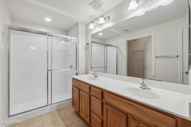 bathroom featuring tile patterned floors, double vanity, a shower stall, and a sink