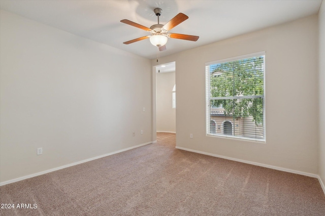 carpeted empty room featuring baseboards and ceiling fan