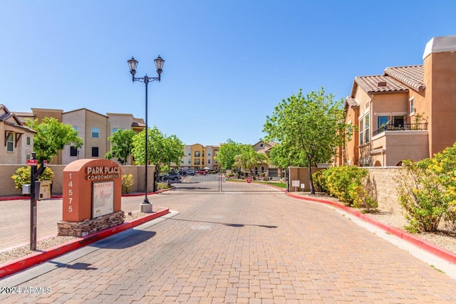 view of road featuring a gate, curbs, street lighting, a gated entry, and a residential view