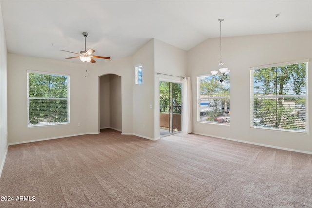 empty room featuring arched walkways, ceiling fan with notable chandelier, lofted ceiling, and carpet