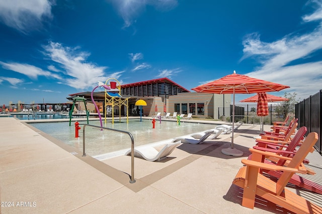 pool featuring a patio area, a water play area, and fence