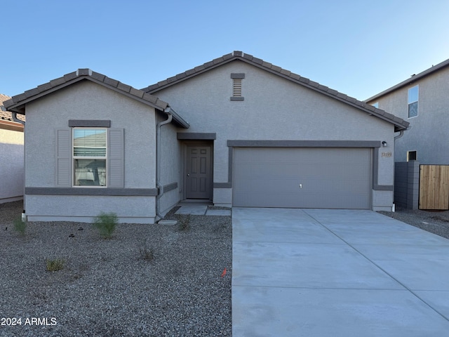 single story home featuring stucco siding, driveway, an attached garage, and a tiled roof