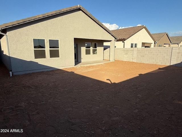 back of property with stucco siding, a patio, a tile roof, and fence