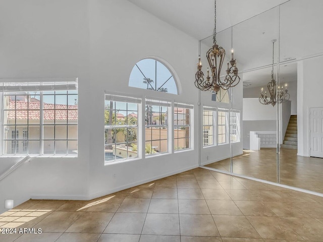 unfurnished dining area featuring high vaulted ceiling, a chandelier, and tile patterned floors