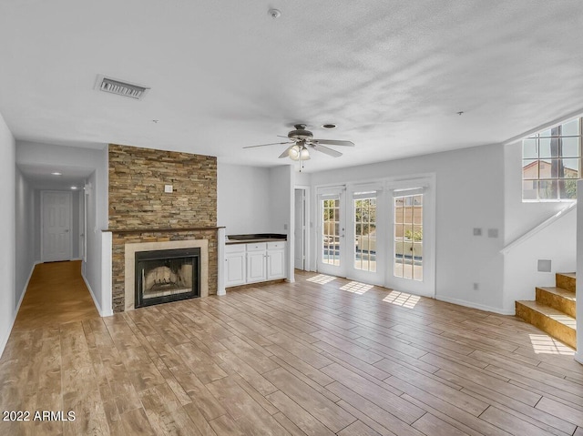 unfurnished living room with a large fireplace, a healthy amount of sunlight, and light hardwood / wood-style flooring