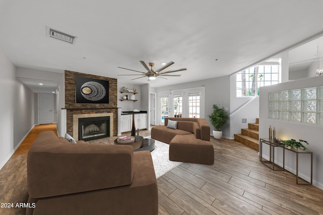 living room featuring light wood-type flooring, ceiling fan, and a fireplace