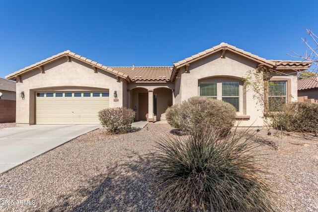 mediterranean / spanish home featuring concrete driveway, an attached garage, a tiled roof, and stucco siding