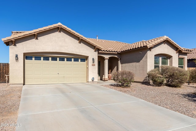 mediterranean / spanish home featuring driveway, an attached garage, a tiled roof, and stucco siding