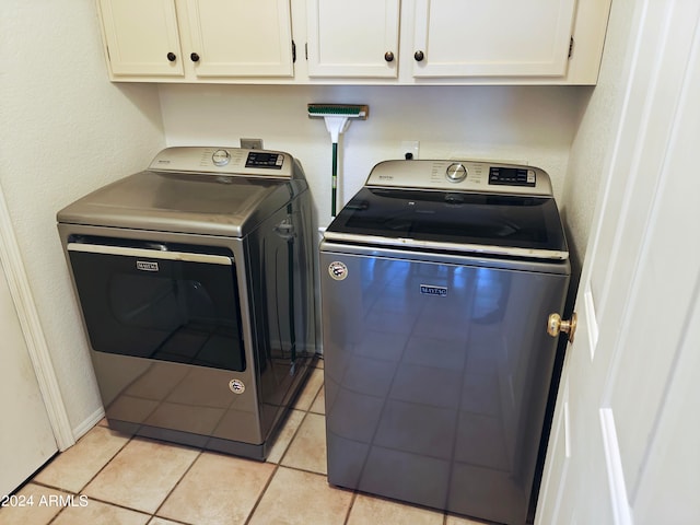 washroom with cabinets, light tile patterned floors, and washer and clothes dryer