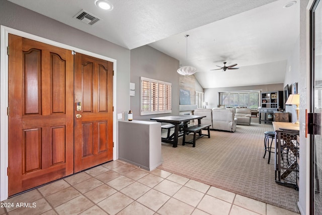 carpeted entryway featuring ceiling fan, a textured ceiling, vaulted ceiling, and a wealth of natural light