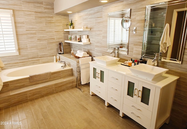 bathroom featuring independent shower and bath, vanity, and tile walls