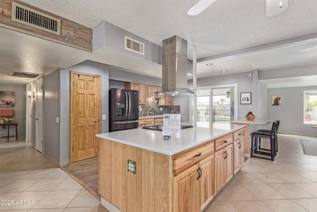 kitchen with light tile patterned flooring, a kitchen island, island range hood, and black appliances