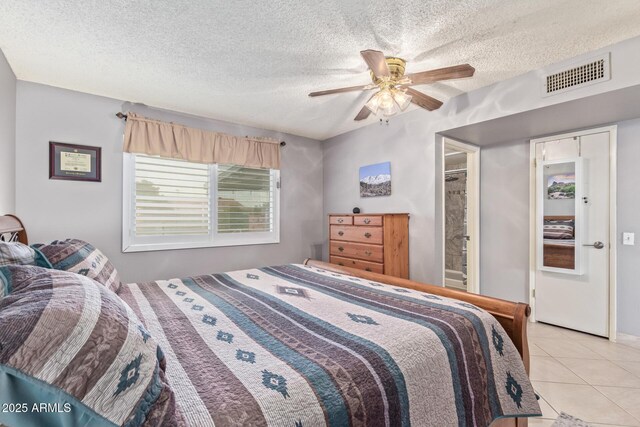 tiled bedroom with ensuite bathroom, a textured ceiling, and ceiling fan