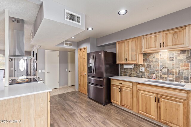 kitchen featuring sink, backsplash, light brown cabinetry, stainless steel fridge with ice dispenser, and light wood-type flooring