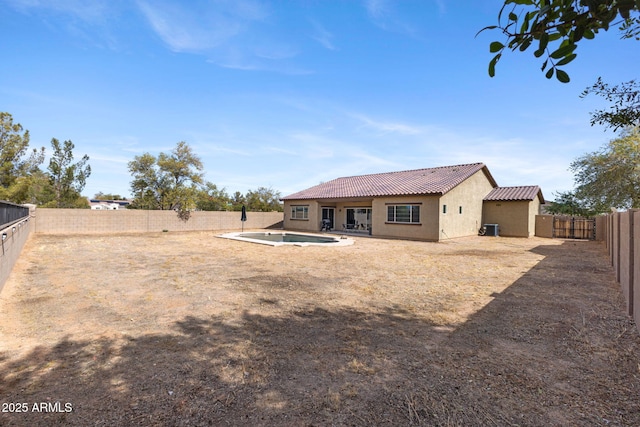 rear view of property featuring a fenced in pool and a patio