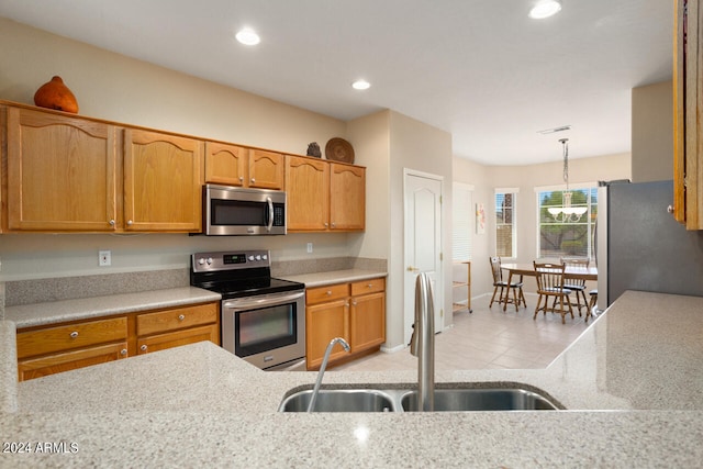 kitchen featuring hanging light fixtures, light tile patterned floors, stainless steel appliances, an inviting chandelier, and sink