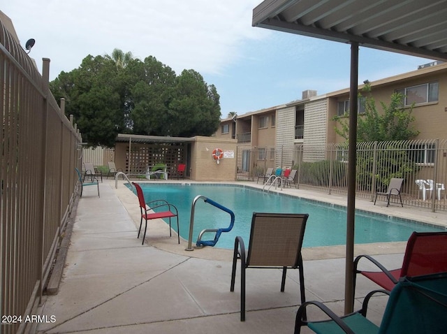 pool with a patio area and fence