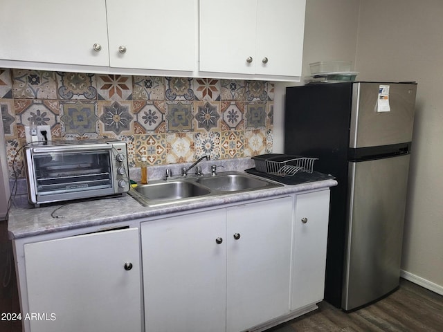 kitchen with white cabinets, a toaster, a sink, tasteful backsplash, and freestanding refrigerator