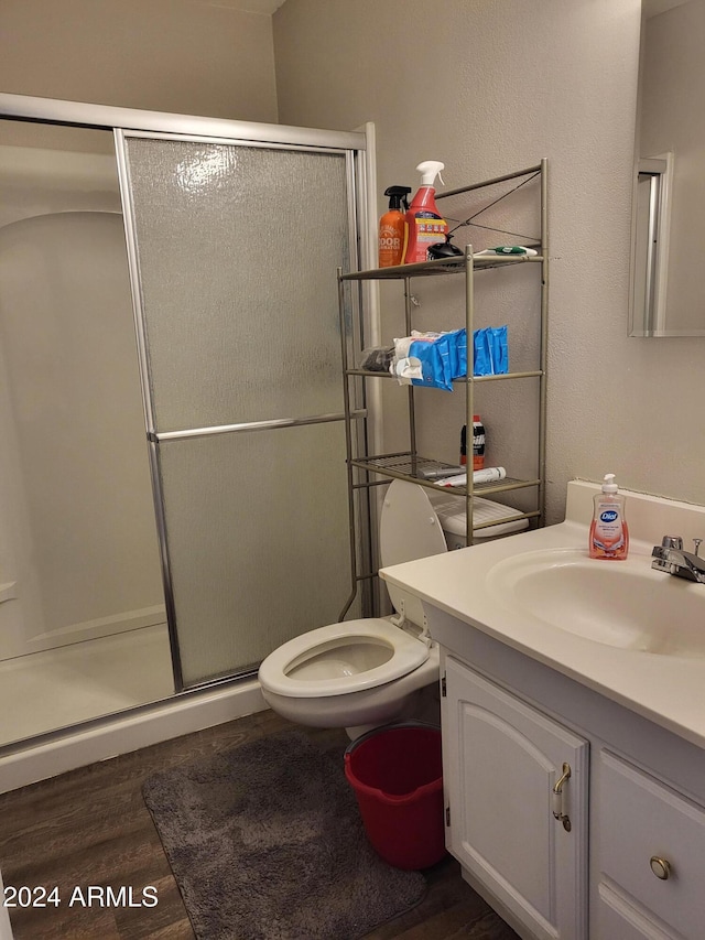 full bathroom with a shower stall, toilet, vanity, and wood finished floors