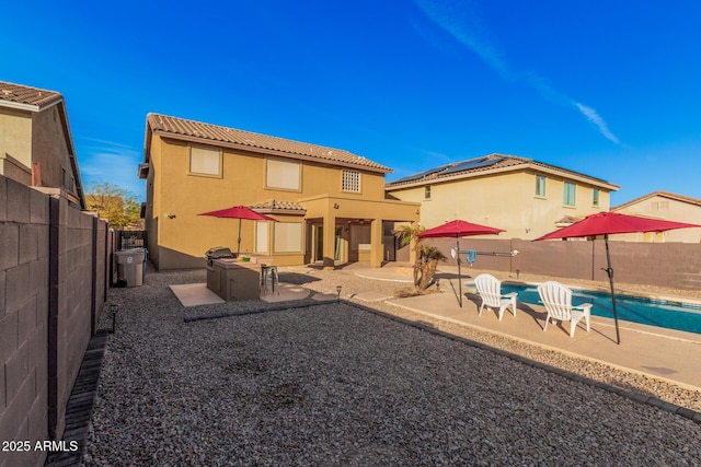 back of house featuring a patio area, solar panels, and a fenced in pool